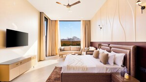 Un dormitorio moderno con una cama grande, un televisor de pantalla plana, un ventilador de techo y vistas al exterior.
