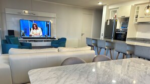 Ein modernes Wohnzimmer mit Fernseher, Sofa und einem Marmortisch.