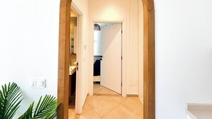 Un couloir avec une arche en bois menant à une salle de bain équipée d’un porte-serviettes et d’une douche.