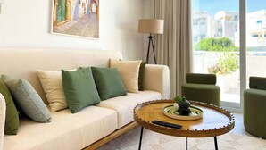 A modern living room with a sofa, a round coffee table, a lamp, and a painting on the wall. - Appartement Nessma 2 Bedrooms (Carthage)