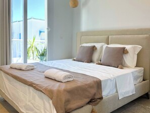 Un lit bien fait, avec une tête de lit beige, du linge de lit blanc et un élément décoratif marron.
