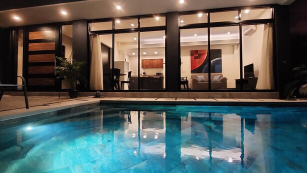 Una casa moderna con piscina, ventanas amplias y un comedor.