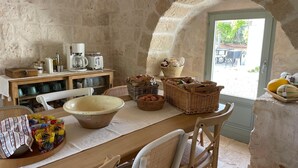 A rustic stone-walled room with a wooden table set for breakfast, including a large bowl, baskets of bread, and a coffee maker. - Olivi estate with private pool in Ceglie 2 and 4/6/8 pax (Ceglie Messapica)