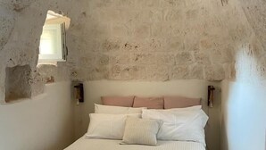 A bedroom with a stone ceiling, a bed with white bedding, and a small window. - Olivi estate with private pool in Ceglie 2 and 4/6/8 pax (Ceglie Messapica)