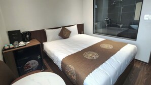 Habitación de hotel con una cama grande, una mesita de noche con cafetera, una bandeja con artículos de desayuno y un ventanal con vista al baño.