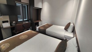 Una habitación de hotel con dos camas, un escritorio, una silla y un ventanal.