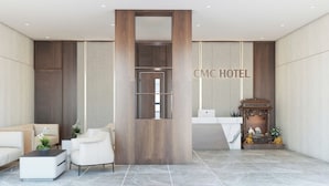 Zona de recepción de hotel con diseño moderno, que incluye un mostrador de recepción, área de descanso y elementos decorativos.