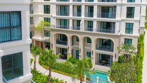 Un hôtel à plusieurs étages doté de balcons, d’une piscine et d’une végétation luxuriante.