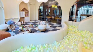 Un espace de jeux avec une piscine à balles, des sièges confortables et un train jouet.