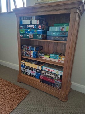 A wooden bookshelf filled with various boxed puzzles.