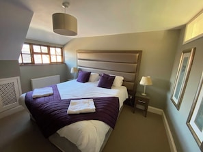 A bedroom with a bed, bedside tables, a window, and a radiator.