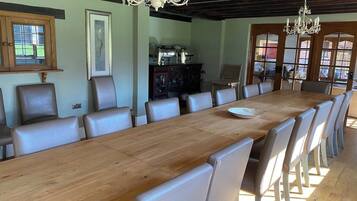 A dining room with a long wooden table, leather chairs, and chandeliers.
