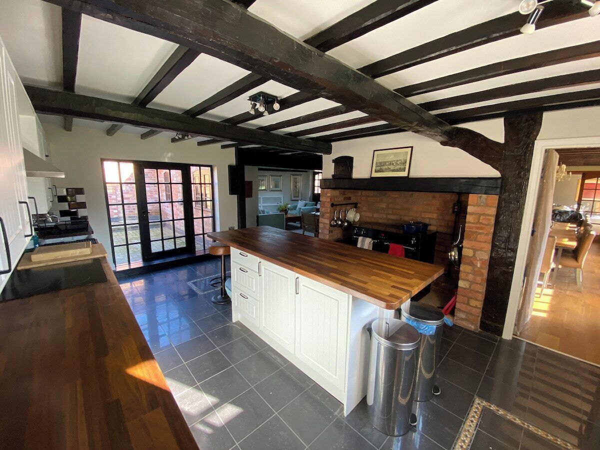 A kitchen with a wooden countertop, white cabinets, and a brick fireplace.
