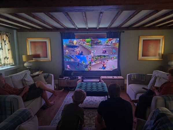 A living room with a television displaying a racing game, a sofa, a coffee table, and a patterned rug.
