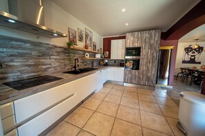 A modern kitchen with a wood-textured backsplash, white cabinets, and a built-in oven. - Magnificent VILLA with a private pool and an exclusive multisport stadium   (Roquebrune-sur-Argens)