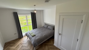 A bedroom with a bed, a window with curtains, a door, and a ceiling light fixture. - Serene 3-Bedroom House in Athlone (Athlone)