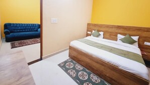 A bedroom with a wooden bed, a blue sofa, and a patterned rug.