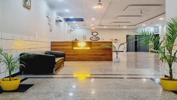 A reception area with a wooden reception desk, black seating, potted plants, and a polished floor.