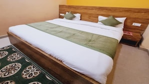 A bed with a wooden headboard, white bedding, and green pillows.