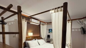 Ein Bett mit Baldachin, hölzernes Kopfteil und ein Nachttisch mit Lampe.