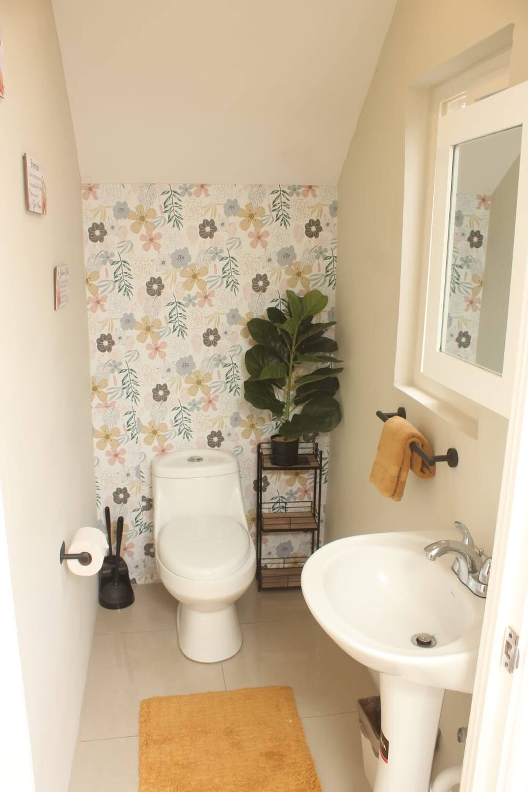 A bathroom with a toilet, sink, and a potted plant.
