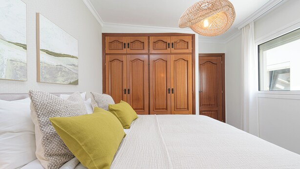 Una camera da letto con un letto grande, un armadio in legno e una lampada a sospensione.