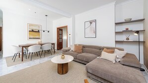 Un soggiorno moderno con un divano componibile, un tavolino rotondo e una zona pranzo con sedie e tavolo.