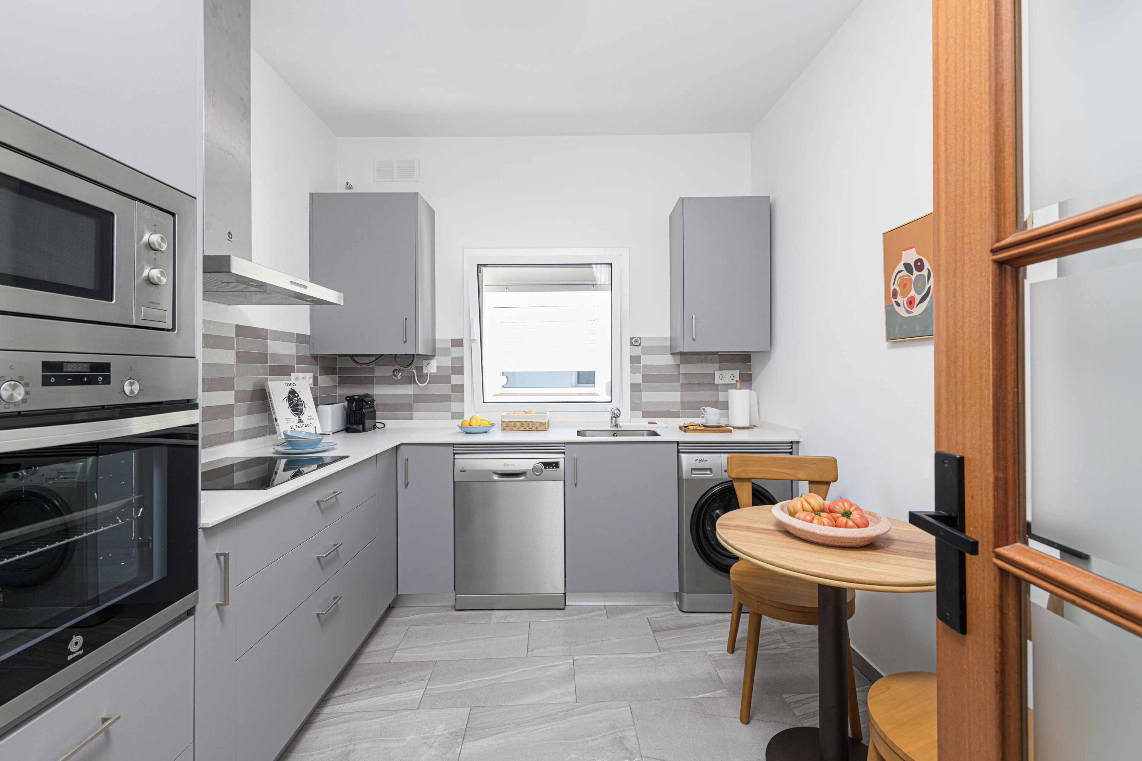 A compact kitchen with built-in appliances, a window, and a dining area with a table and chairs.