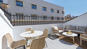 Una terrazza sul tetto con mobili in vimini, un tavolo rotondo e un divano.