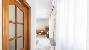 Un corridoio con una porta in legno, una parete bianca e un pavimento in marmo.