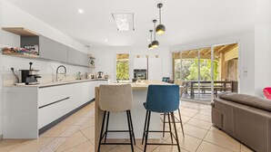 A modern kitchen with a central island, bar stools, and a dining area with a view. - Bed and Breakfast 'Nimes' with Shared Pool, Shared Terrace and Wi-Fi (Nîmes)