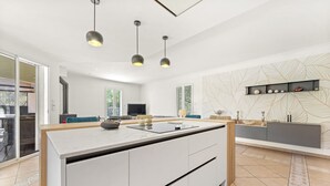 A modern kitchen with a central island, pendant lighting, and a decorative wall pattern. - Bed and Breakfast 'Nimes' with Shared Pool, Shared Terrace and Wi-Fi (Nîmes)