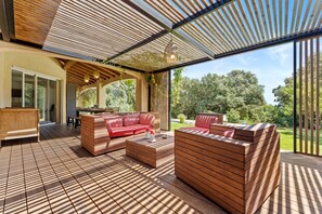 An outdoor living area with wooden furniture, a pergola, and a view of the surrounding greenery. - Bed and Breakfast 'Nimes' with Shared Pool, Shared Terrace and Wi-Fi (Nîmes)