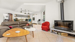 A modern living room with a sofa, coffee table, fireplace, and kitchen in the background. - Bed and Breakfast 'Nimes' with Shared Pool, Shared Terrace and Wi-Fi (Nîmes)