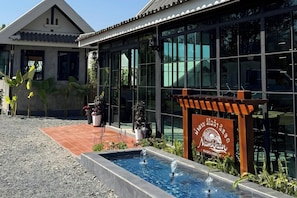 A resort with a swimming pool, a signboard, and a building with large windows. - Namkhan Revora Resort (Luang Prabang)