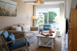 Un salon comprenant un canapé, un fauteuil, une table basse et un téléviseur.
