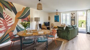 Uma sala de jantar com uma mesa redonda, cadeiras e um vaso de flores.