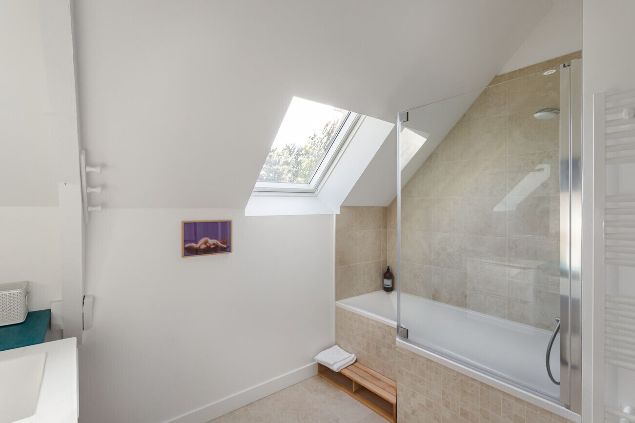 A modern bathroom with a skylight, a bathtub, and a shower area.
