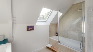 Uma casa de banho moderna com clarabóia, banheira e zona de duche.