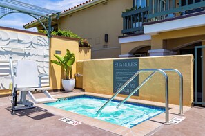 A spa pool with a sign listing rules and a lifeguard chair.