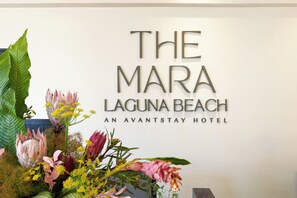 A sign for The Mara Laguna Beach, an avant-stay hotel, with a floral arrangement in front. - Ocean Views + Pool + Hot Tub| Walk to Beach + Laguna Attractions + Dining (Laguna Beach)