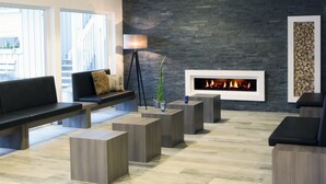 A modern lounge area with a fireplace, seating, and a view of the outside. - Hotel & Tagungszentrum Blaubeuren (Blaubeuren)