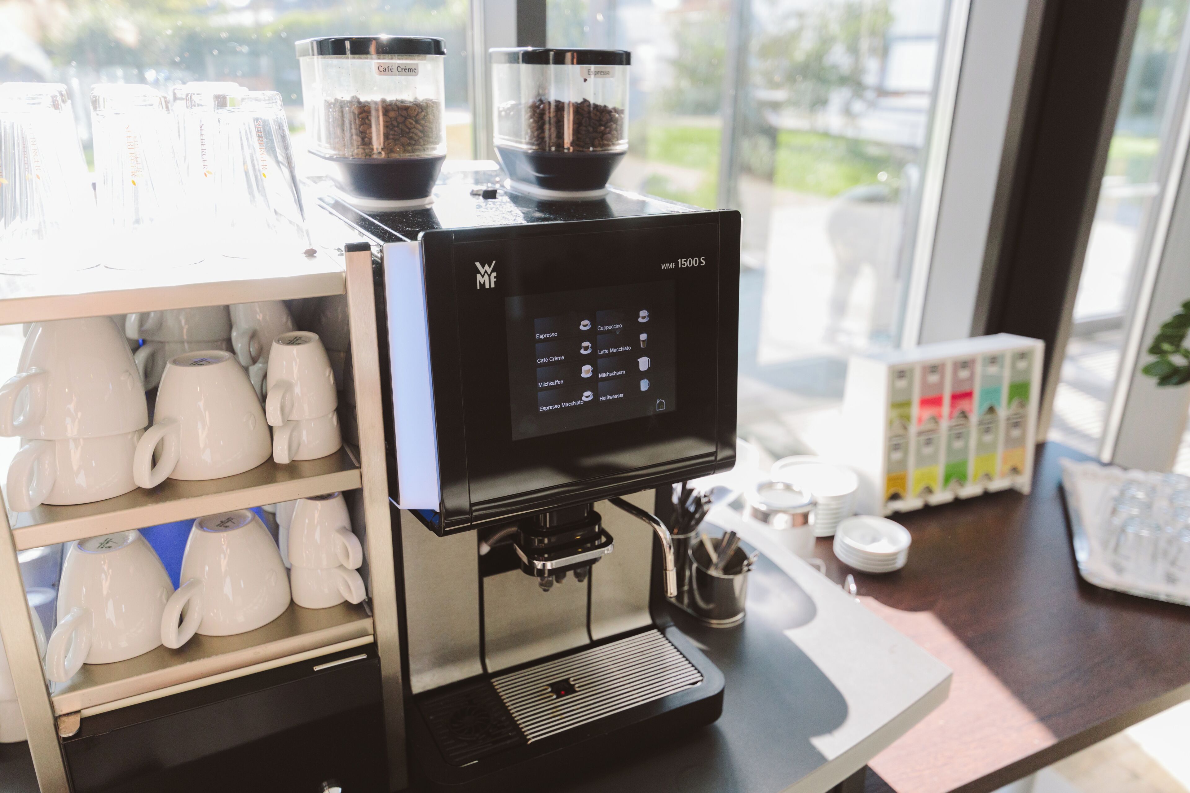 Een koffieapparaat met een digitaal scherm, koffiebonen en een bekerrek.