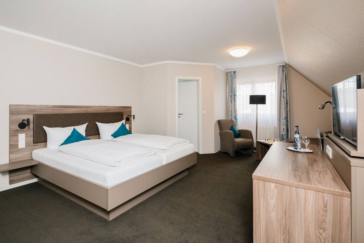 Ein Hotelzimmer mit Bett, Schreibtisch mit Fernseher, Stuhl und Lampe.