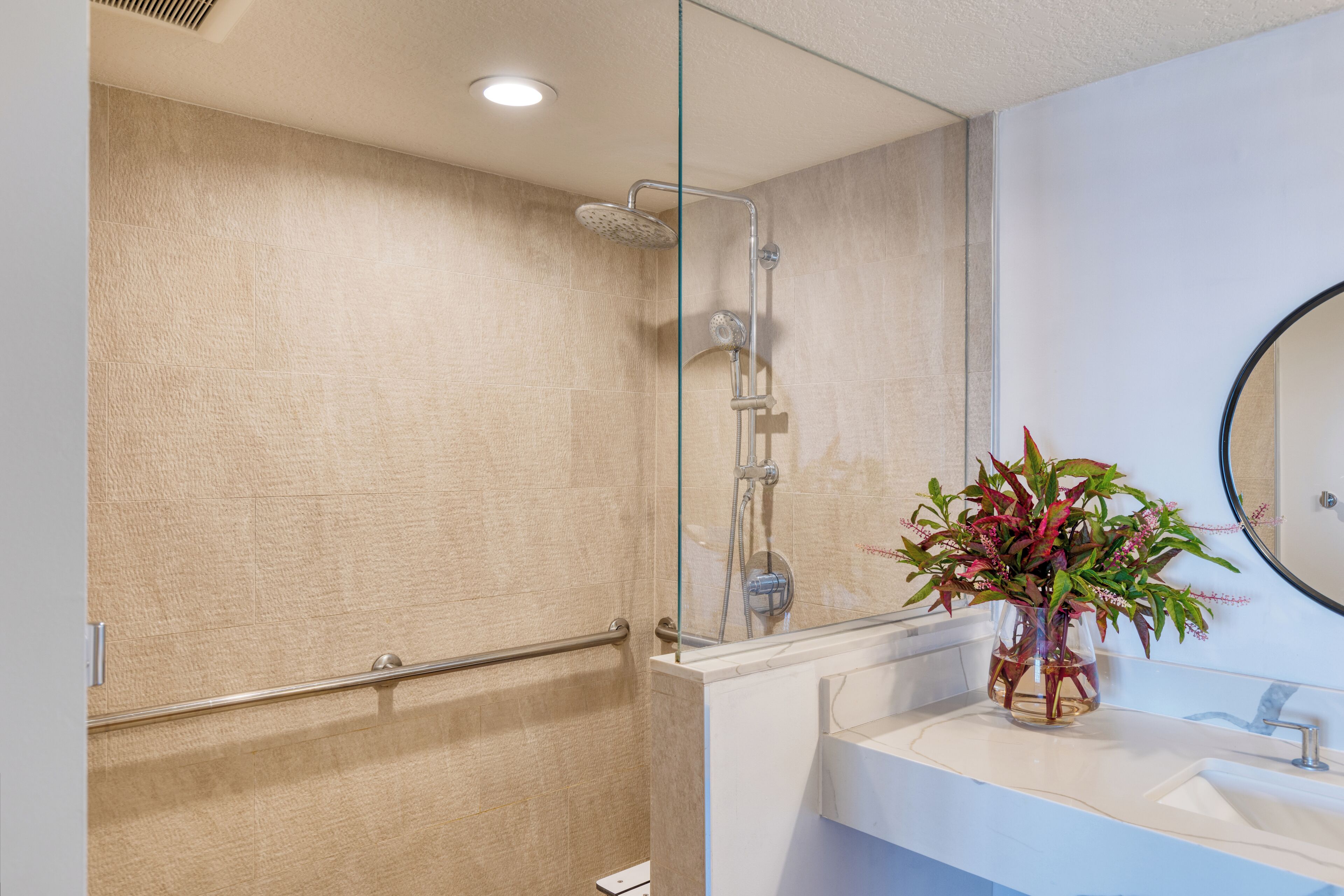 Un baño moderno con cabina de ducha de vidrio, un lavabo blanco y un espejo.