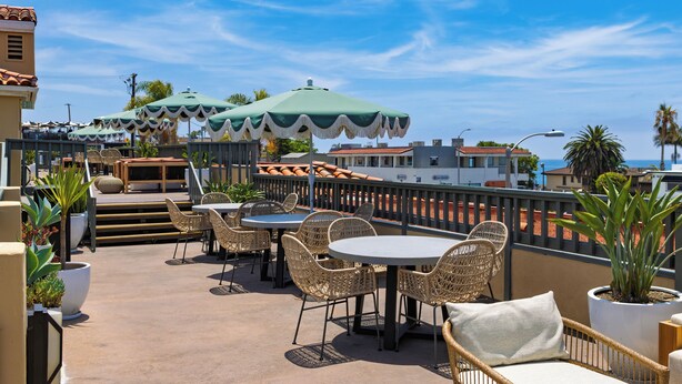 Une terrasse extérieure aménagée avec des meubles en osier, des parasols et des plantes en pot.