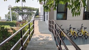 Rampa accesible para sillas de ruedas que lleva a un edificio de fachada blanca con una fila de bicicletas amarillas estacionadas afuera.