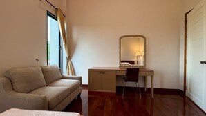 Una habitación con cama, escritorio, silla, ventana con cortinas y puerta.