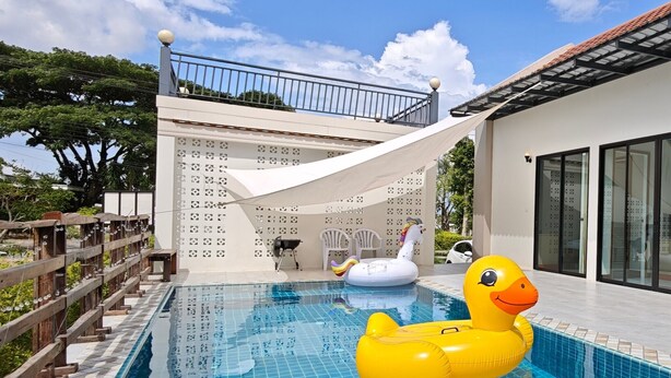 Una piscina con un flotador de pato, un porche cubierto y vistas a un edificio de paredes con diseños.