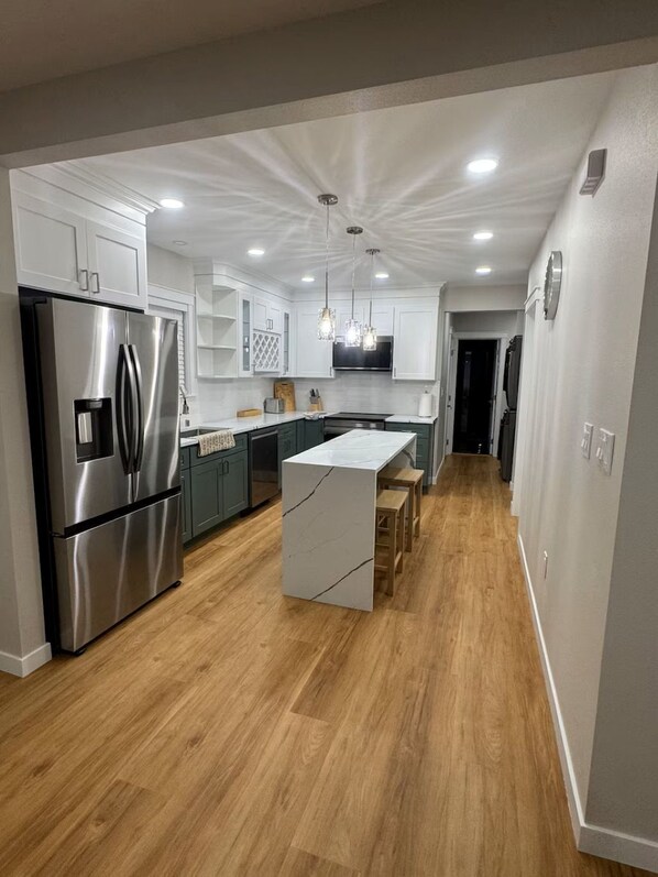 Una cocina moderna con una isla central, electrodomésticos de acero inoxidable e iluminación colgante.